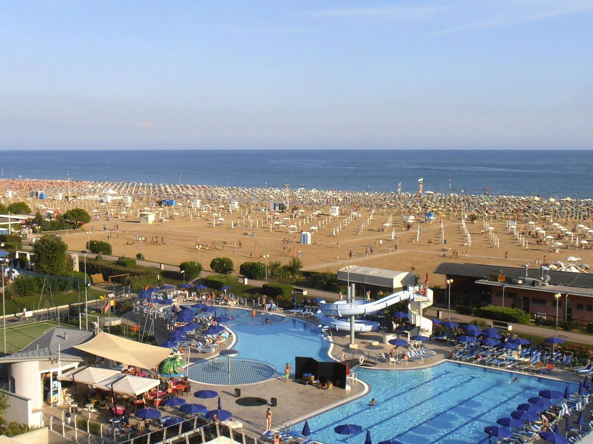 Veduta aerea della spiaggia sabbiosa di Bibione con piscine e campi sportivi sul retro